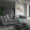 A greyi velvet Buxton 3 seater sofa in a living room with a painting on the wall and a coffee table in front of the sofa. The sofa is similar in shape to a traditional Chesterfield sofa, with curving lines to the arms, but has square cushions at the back.